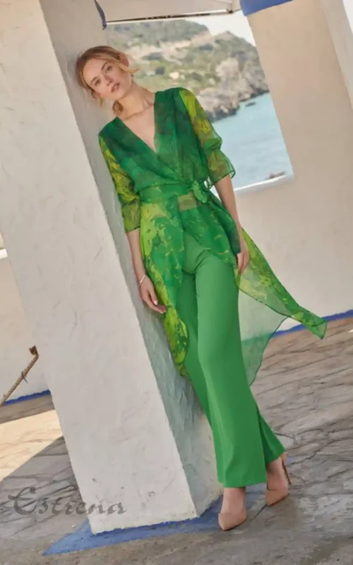 Mujer apoyada en columna con conjunto verde de túnica asimétrica estampada y pantalón fluido de fiesta en Cartagena.