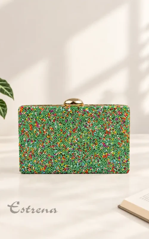 Bolso de mano rígido tipo clutch decorado con pedrería fina multicolor sobre fondo verde y un cierre de metal dorado.