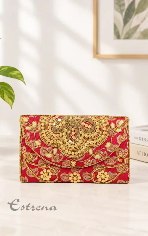 Bolso estilo cartera de fiesta color rojo con bordados artesanales y lentejuelas doradas sobre una mesa