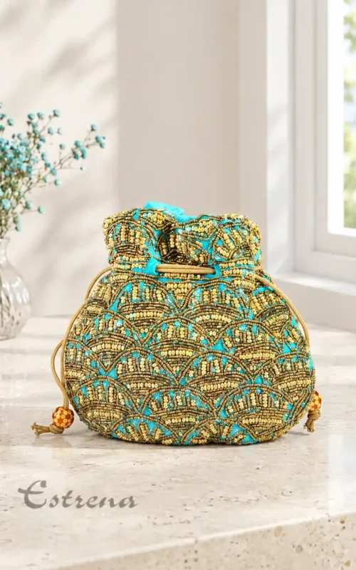 Bolso potli de fiesta turquesa con bordados dorados en pedrería sobre una mesa