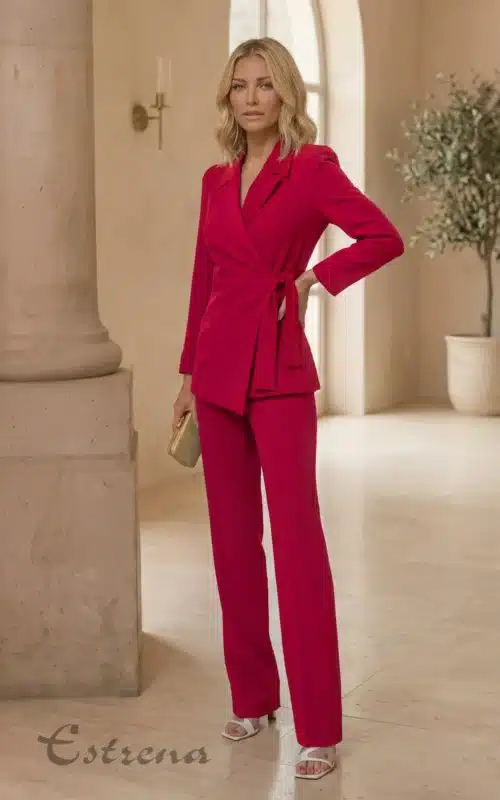 Modelo rubia posando con un traje sastre fucsia de chaqueta cruzada con lazo en la cintura y pantalón recto.
