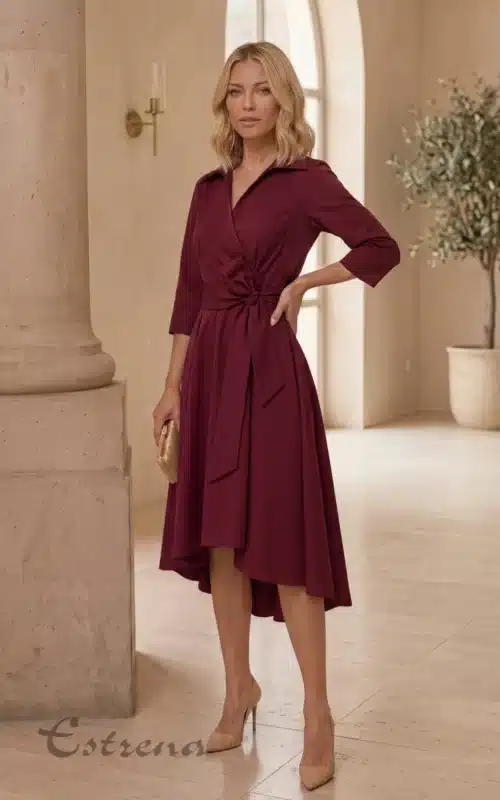 Mujer rubia luciendo un vestido midi camisero cruzado burdeos con lazo y tacones nude en un salón clásico.